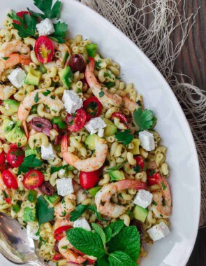 Mediterranean Pasta Salad | The Mediterranean Dish. Easy shrimp and avocado Mediterranean pasta salad. A light and zesty Mediterranean dressing, and tons of fresh herbs, chopped veggies, olives and more, take this shrimp pasta salad to a new level of delicious! See the full recipe on TheMediterraneanDish.com. #pastasalad #mediterraneanrecipe #mediterraneandiet #shrimppastasalad