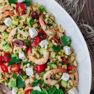 Mediterranean Pasta Salad | The Mediterranean Dish. Easy shrimp and avocado Mediterranean pasta salad. A light and zesty Mediterranean dressing, and tons of fresh herbs, chopped veggies, olives and more, take this shrimp pasta salad to a new level of delicious! See the full recipe on TheMediterraneanDish.com. #pastasalad #mediterraneanrecipe #mediterraneandiet #shrimppastasalad