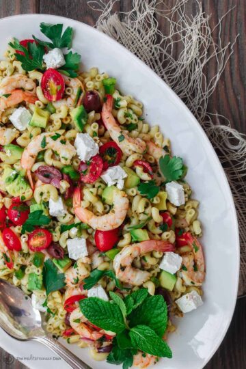 Mediterranean Pasta Salad | The Mediterranean Dish. Easy shrimp and avocado Mediterranean pasta salad. A light and zesty Mediterranean dressing, and tons of fresh herbs, chopped veggies, olives and more, take this shrimp pasta salad to a new level of delicious! See the full recipe on TheMediterraneanDish.com. #pastasalad #mediterraneanrecipe #mediterraneandiet #shrimppastasalad