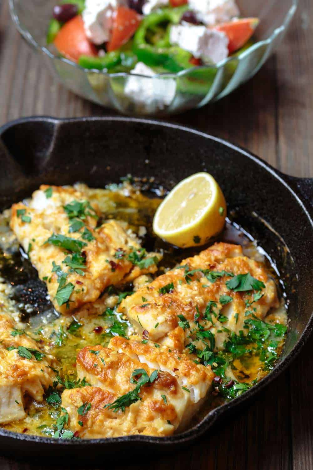 Baked cod in skillet with a side of Greek salad