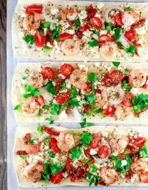 Mediterranean Shrimp Flatbread Pizza | The Mediterranean Dish. Easiest ever shrimp pizza on flatbread with Mediterranean favorites like feta, shallots, and sun-dried tomatoes. Takes less than 15 minutes start-to-finish! See the easy recipe on TheMediterraneanDish.com