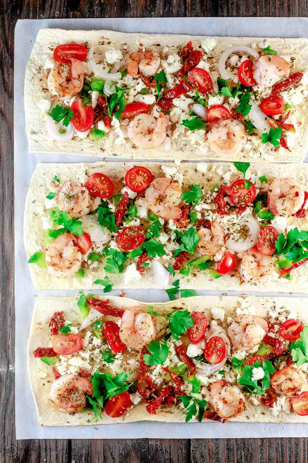 Mediterranean Shrimp Flatbread Pizza | The Mediterranean Dish. Easiest ever shrimp pizza on flatbread with Mediterranean favorites like feta, shallots, and sun-dried tomatoes. Takes less than 15 minutes start-to-finish! See the easy recipe on TheMediterraneanDish.com