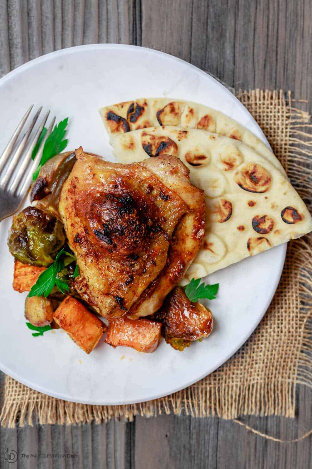 Chicken thigh, Vegetables and pita bread serves on a plate