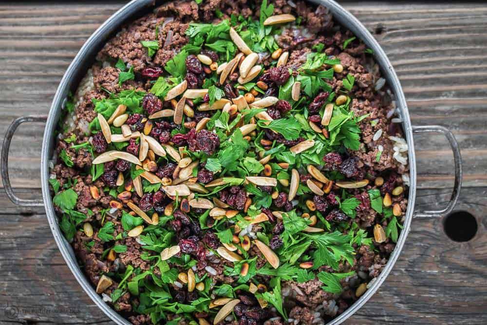 Turn Hashweh Rice over on to a serving plate so that the meat mixture is on top. Add nuts and raisins