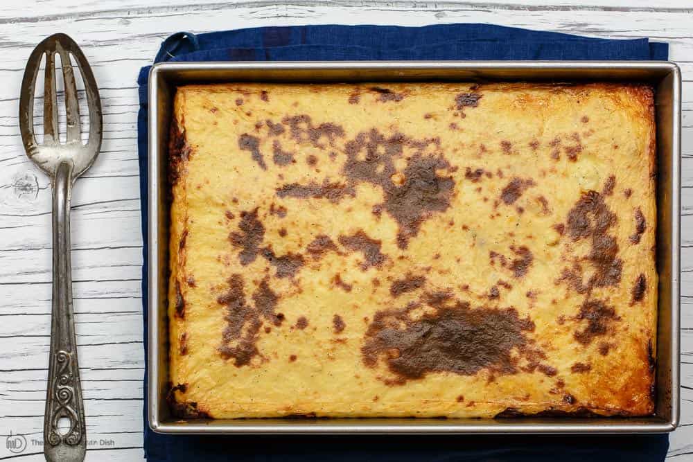 baked pastitsio in a baking dish with a serving spoon