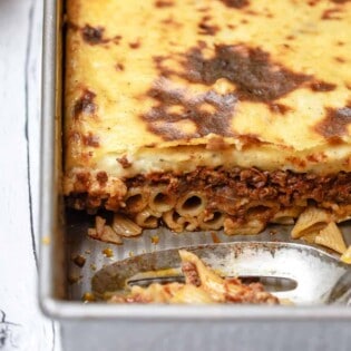 Piece of Greek lasagna cut out of the baking dish