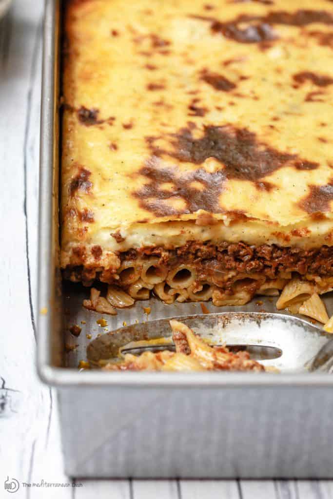 Piece of Greek lasagna cut out of the baking dish