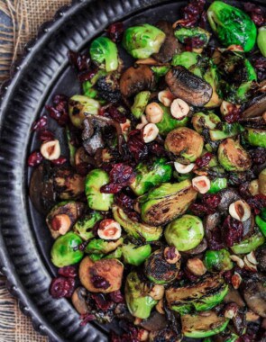 Olive Oil Fried Brussels Sprouts | The Mediterranean Dish. Simple olive oil fried sprouts with mushrooms, cranberries, and hazelnuts, makes a festive vegan and gluten free side dish. See full recipe on TheMediterraneanDish.com #mediterraneanrecipe #friedbrusselssprouts #brusselssprouts #thanskgivingdinner #holidaysidedish #sidedish