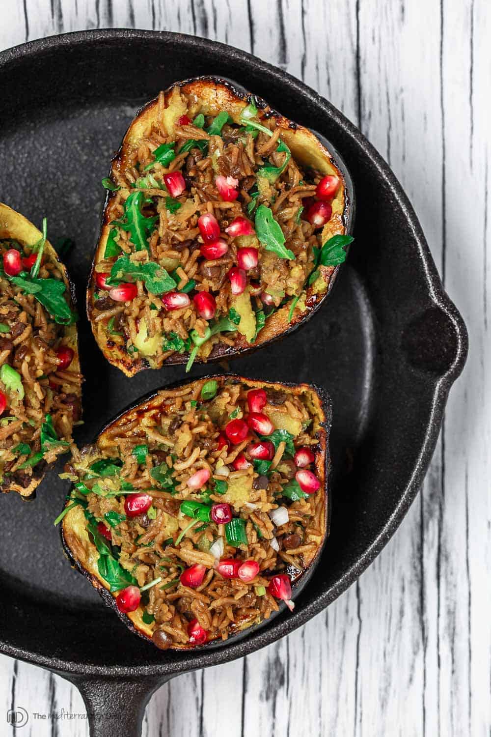 Mediterranean Style Stuffed Acorn Squash Recipe | The Mediterranean Dish.Simple all-start stuffed acorn squash recipe! Prepared Mediterranean-style with an easy rice and lentil pilaf mixture with fresh herbs and pomegranate seeds. A major shortcut makes all the difference! See the recipe on TheMediterraneanDish.com #acornsquash #mediterraneanrecipe #roastedsquash #squashrecipe #thanksigivngdinner 
