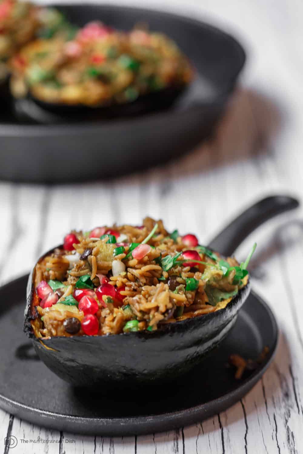 Mediterranean Style Stuffed Acorn Squash Recipe | The Mediterranean Dish.Simple all-start stuffed acorn squash recipe! Prepared Mediterranean-style with an easy rice and lentil pilaf mixture with fresh herbs and pomegranate seeds. A major shortcut makes all the difference! See the recipe on TheMediterraneanDish.com #acornsquash #mediterraneanrecipe #roastedsquash #squashrecipe #thanksigivngdinner 