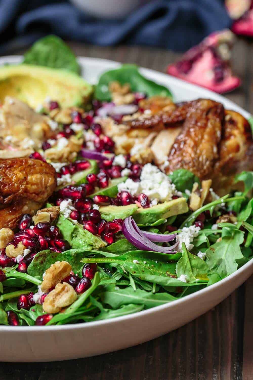 Close-up of Chicken Arugula Salad garnished with pomegranate seeds and chopped nuts