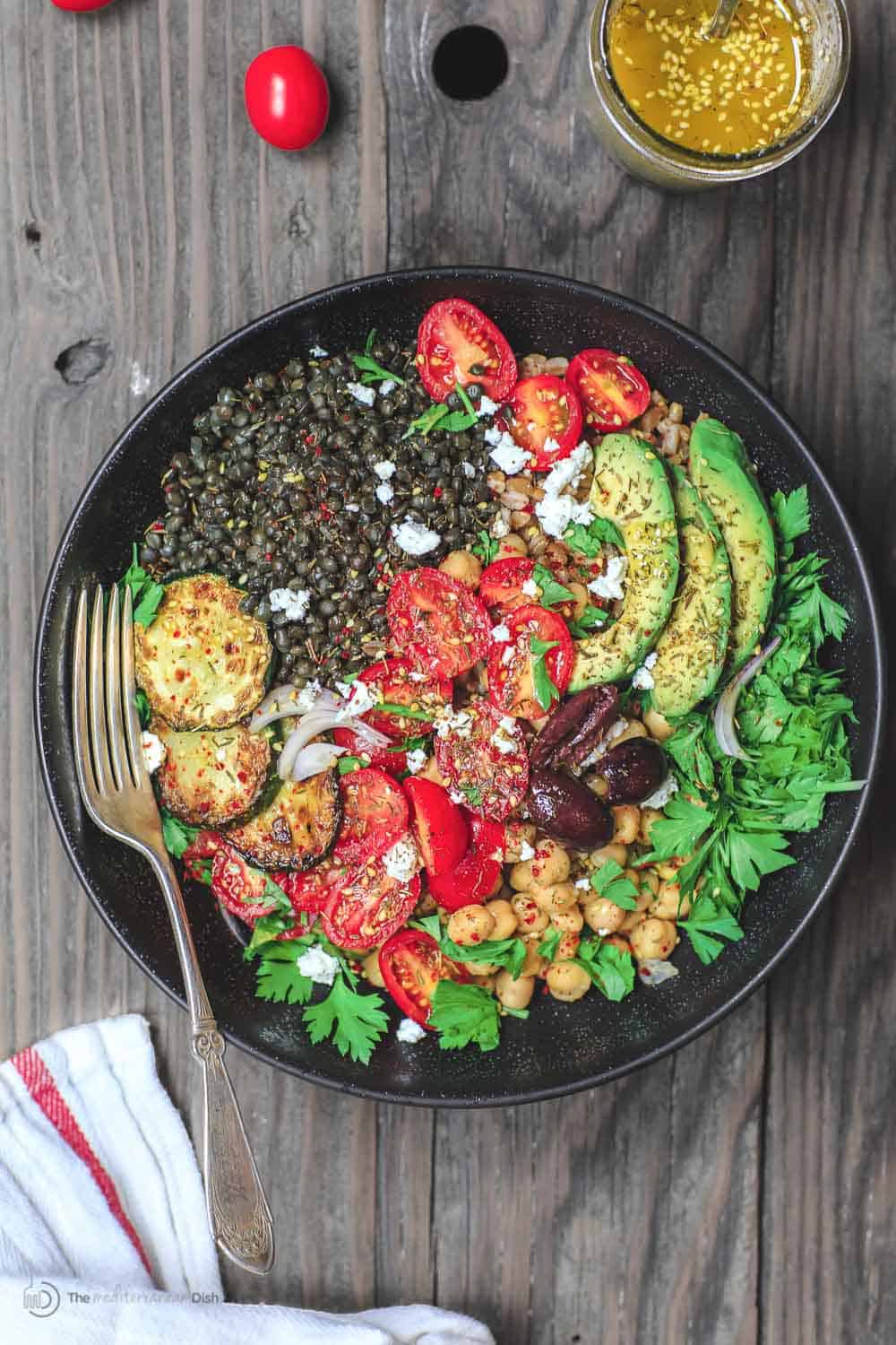 Mediterranean Grain Bowls with lentils, zucchini, avocados, tomatoes and topped with feta cheese.
