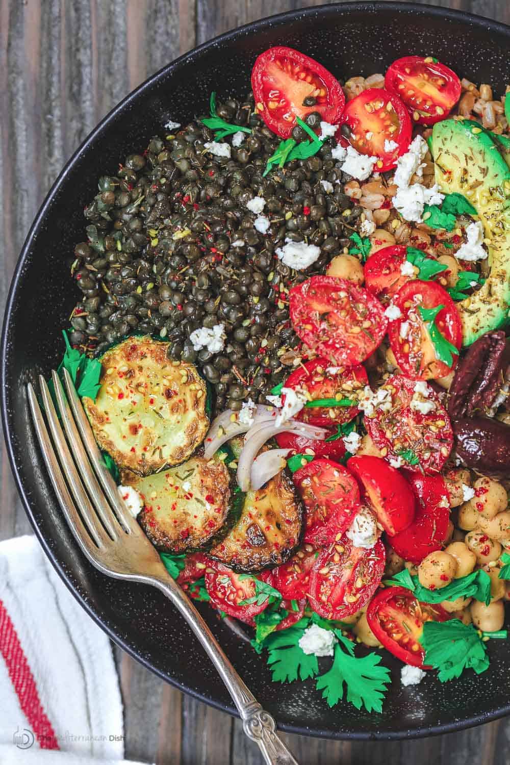 Mediterranean Grain Bowls with lentils, zucchini, avocados, tomatoes and topped with feta cheese.