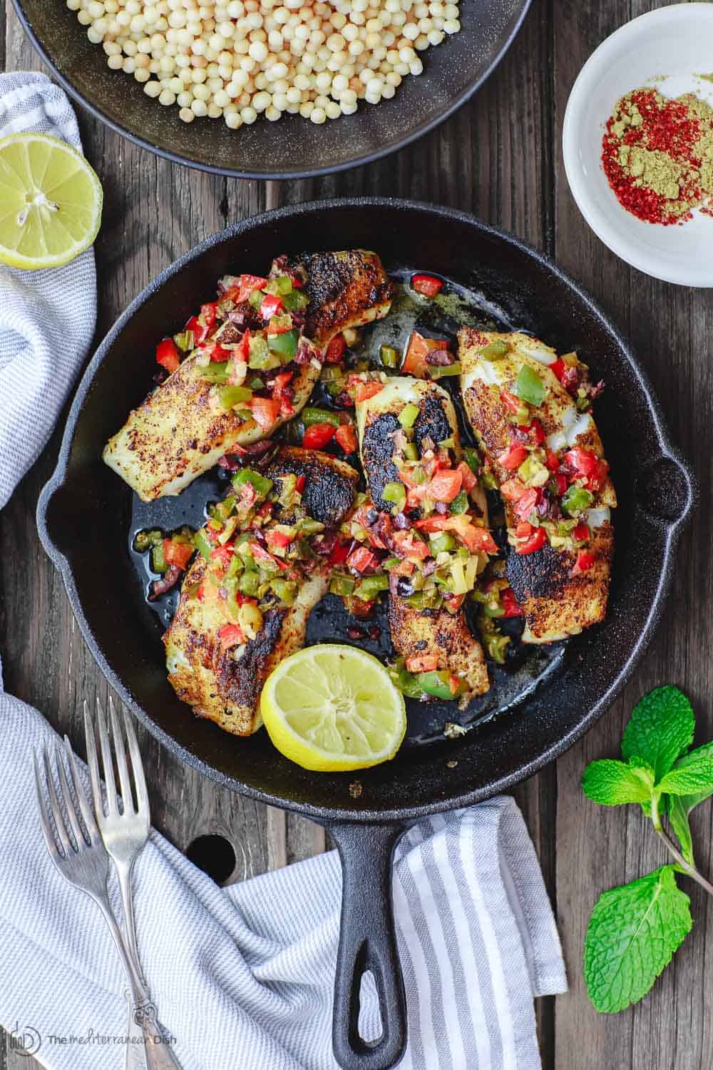 Mediterranean Pan Seared Sea Bass Recipe | The Mediterranean Dish. Quick and crispy pan seared sea bass, coated with Mediterranean spices and a tasty bell pepper medley to serve on top or as a side! Dinner in minutes! from TheMediterraneanDish.com #mediterraneandiet #mediterraneanrecipes #seafoodrecipes #fish #fishrecipes #healthyrecipes #lowcarbrecipes #weeknightdinner #weeknightmeal #onpotdinner #onepan #glutenfreerecipes #seabass #easyrecipes