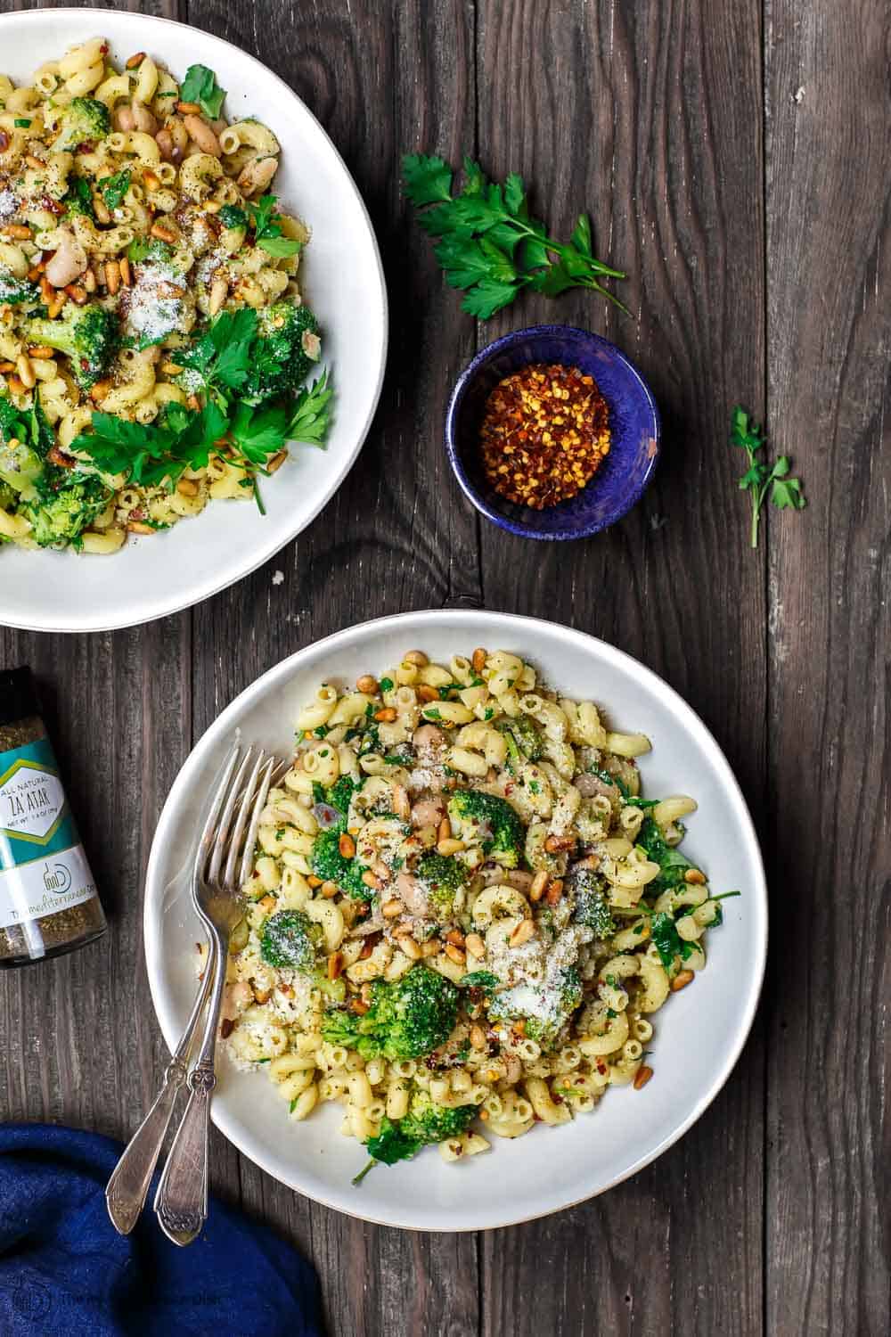 Broccoli pasta served in two bowls, a side of crushed pepper flakes and za'atar