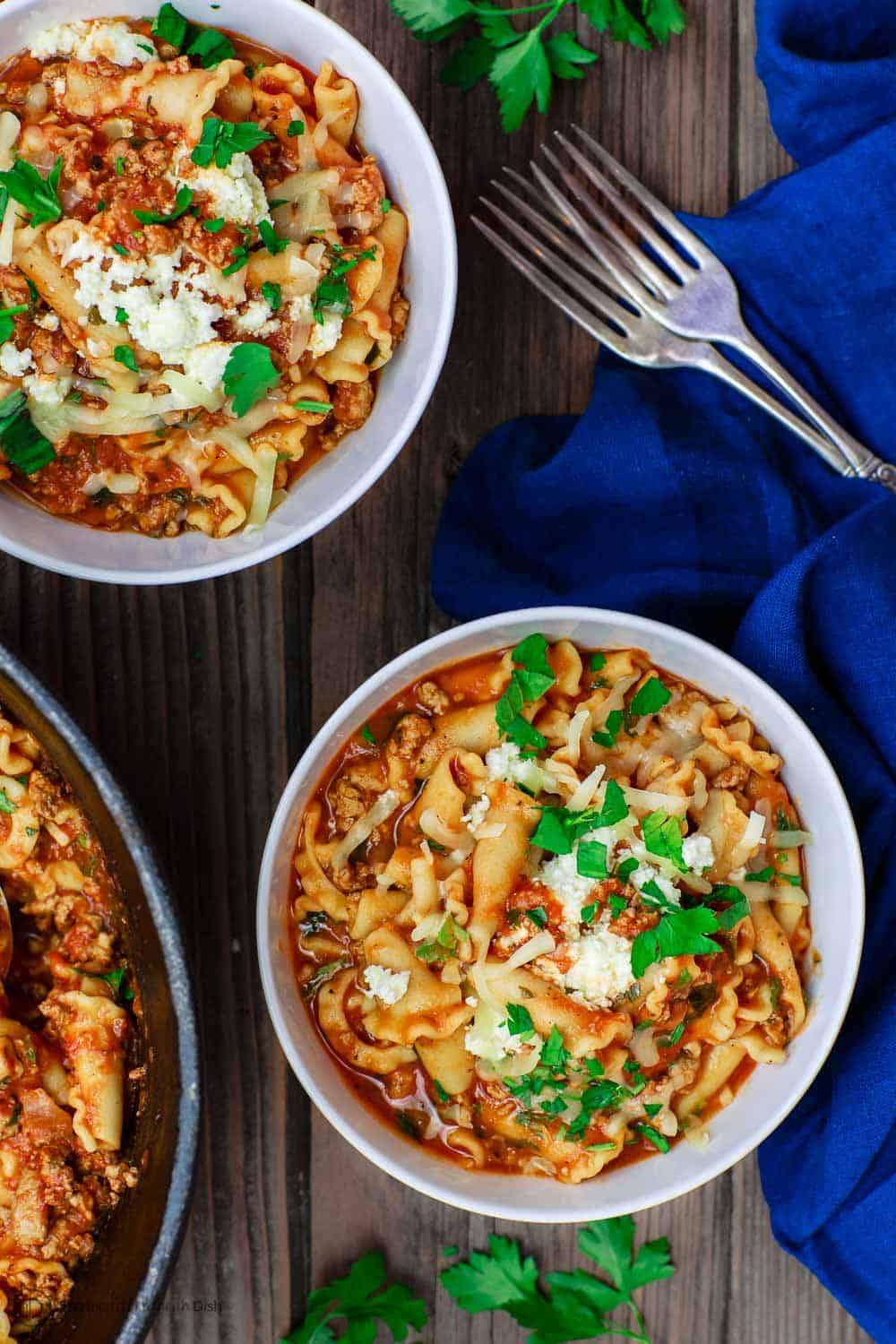 Bowls of Turkey Lasagna Soup served with some extra fresh parsley on the side