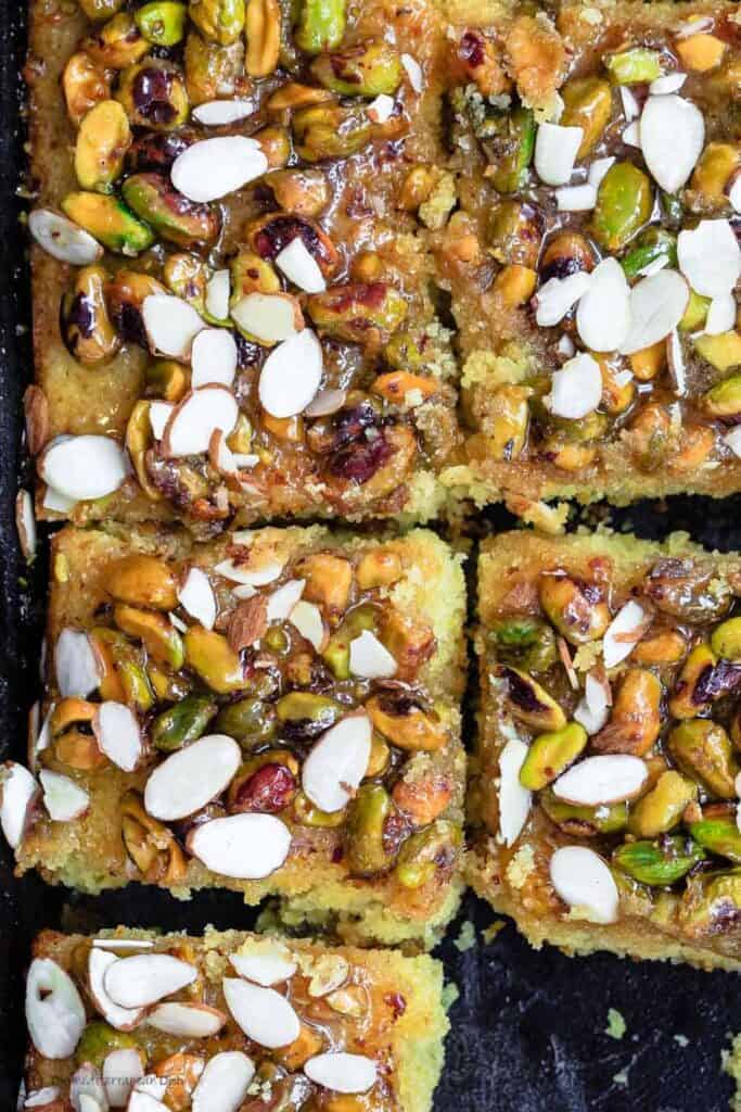Greek Orange Honey Cake | The Mediterranean Dish. This super simple Greek cake is made with olive oil and Greek yogurt, and perfectly flavored with lots of citrus. Topped with toasted pistachios and a luscious honey syrup. A foolproof honey cake that can feed a crowd! See it on TheMediterraneanDish.com #cake #oliveoilcake #mediterraneandiet #easterdinnerideas #easterdinner #dessertrecipes #chirstmasrecipes #christmasdinnerideas #easterrecipes