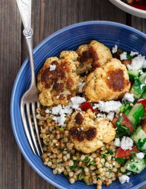 Herbed Couscous Recipe with Roasted Cauliflower | The Mediterranean Dish. Perfectly satisfying dinner bowls with flavor-packed herb couscous, perfectly roasted cauliflower, and an easy Mediterranean salad. Recipe comes with tips for best roasted cauliflower! Omit the feta for vegan dinner bowls. Recipe from TheMediterraneanDish.com