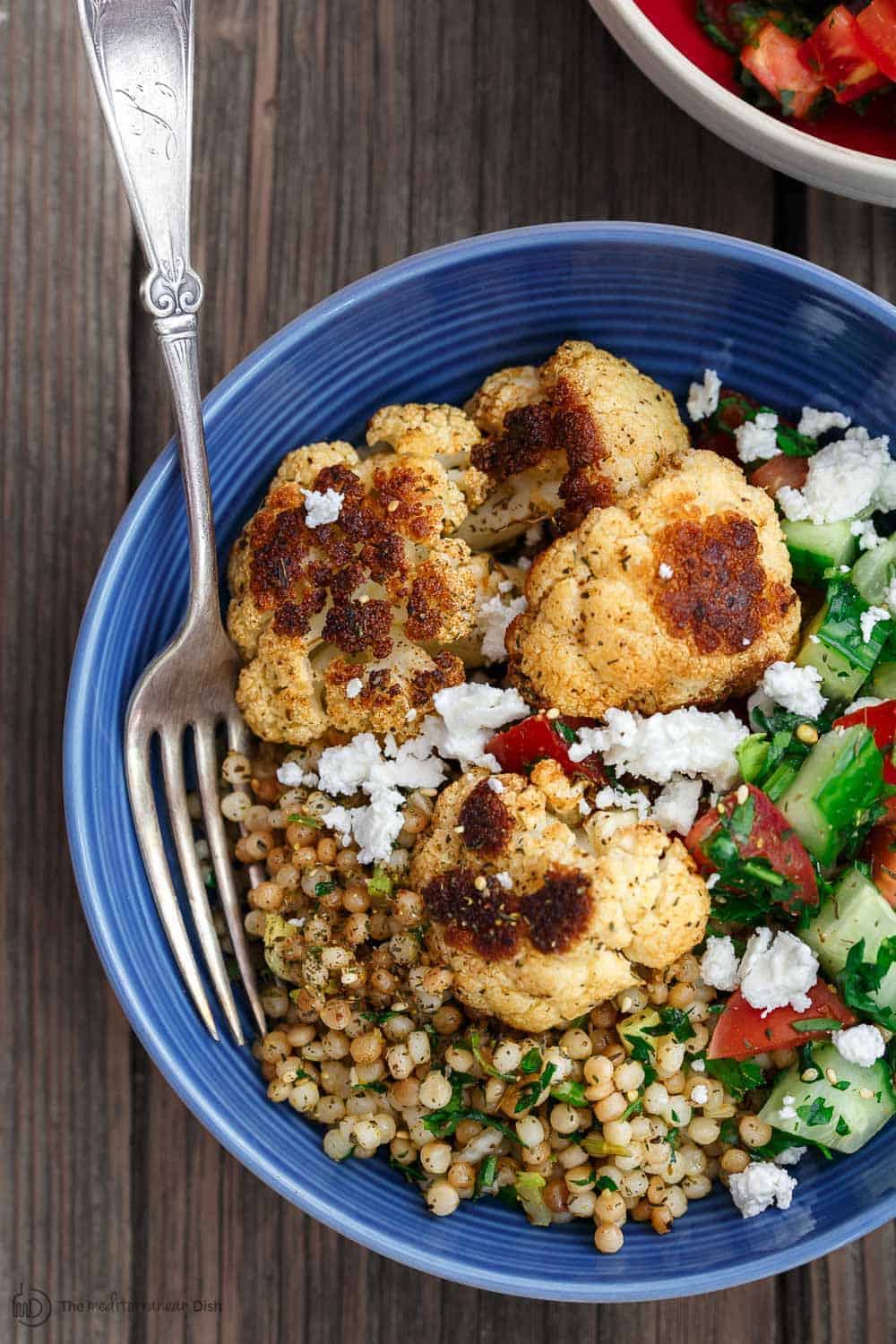 Herbed Couscous Recipe with Roasted Cauliflower | The Mediterranean Dish. Perfectly satisfying dinner bowls with flavor-packed herb couscous, perfectly roasted cauliflower, and an easy Mediterranean salad. Recipe comes with tips for best roasted cauliflower! Omit the feta for vegan dinner bowls. Recipe from TheMediterraneanDish.com