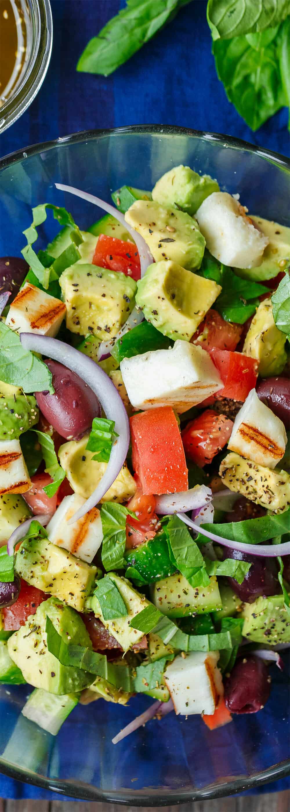 Simple Mediterranean Avocado Salad | The Mediterranean Dish. The BEST avocado salad, prepared Mediterranean style with tomatoes, cucumbers and a the perfect garlic vinaigrette! Use grilled halloumi cheese for croutons, or leave them out for a vegan option. #avocado #avocadosalad #mediterraneandiet #mediterraneanfood #salad #avocados #vegetarianrecipes #glutenfree