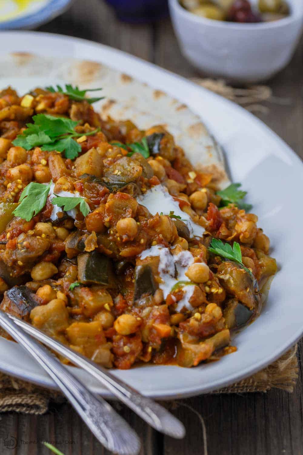 Greek Style Braised Eggplant Recipe | The Mediterranean Dish.All star braised eggplant recipe, prepared Greek style! Eggplants cooked to velvety tender perfection with chickpeas and tomato with aromatics and a few awesome spices. A perfectly satisfying meatless dinner or side dish. Vegan. Gluten Free. #meatless #eggplantrecipe #chickpearecipe #mediterraneandiet #greekfood #veganrecipe #glutenfreerecipe #chickpeas #eggplant #meatlessdinner #onepot #easyrecipes #healthyrecipe #vegetarian