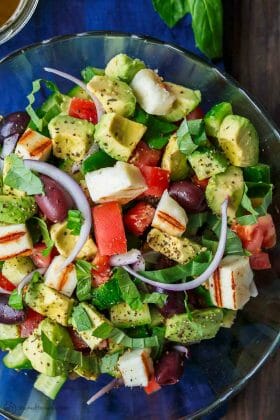 Simple Mediterranean Avocado Salad | The Mediterranean Dish. The BEST avocado salad, prepared Mediterranean style with tomatoes, cucumbers and a the perfect garlic vinaigrette! Use grilled halloumi cheese for croutons, or leave them out for a vegan option. #avocado #avocadosalad #mediterraneandiet #mediterraneanfood #salad #avocados #vegetarianrecipes #glutenfree