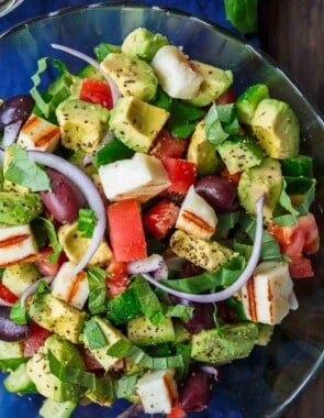 Simple Mediterranean Avocado Salad | The Mediterranean Dish. The BEST avocado salad, prepared Mediterranean style with tomatoes, cucumbers and a the perfect garlic vinaigrette! Use grilled halloumi cheese for croutons, or leave them out for a vegan option. #avocado #avocadosalad #mediterraneandiet #mediterraneanfood #salad #avocados #vegetarianrecipes #glutenfree