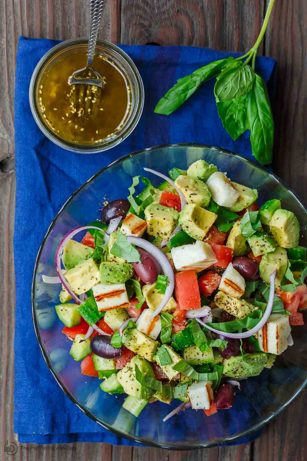 Simple Mediterranean Avocado Salad | The Mediterranean Dish. The BEST avocado salad, prepared Mediterranean style with tomatoes, cucumbers and a the perfect garlic vinaigrette! Use grilled halloumi cheese for croutons, or leave them out for a vegan option. #avocado #avocadosalad #mediterraneandiet #mediterraneanfood #salad #avocados #vegetarianrecipes #glutenfree