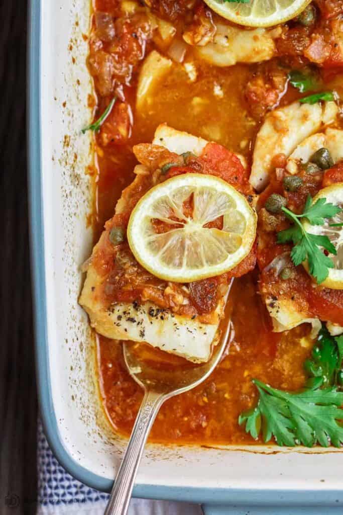 Mediterranean Baked Fish Recipe with Tomatoes and Capers | The Mediterranean Dish. Easy, bright, flavor-packed baked fish, prepared Mediterranean style with spices, tomatoes and capers. From TheMediterraneanDish.com #healthyrecipes #fishrecipe #bakedfish #cod #halibut #glutenfree #seafoodrecipe #seafood #fish #mediterraneandiet #mediterranean #easyrecipe