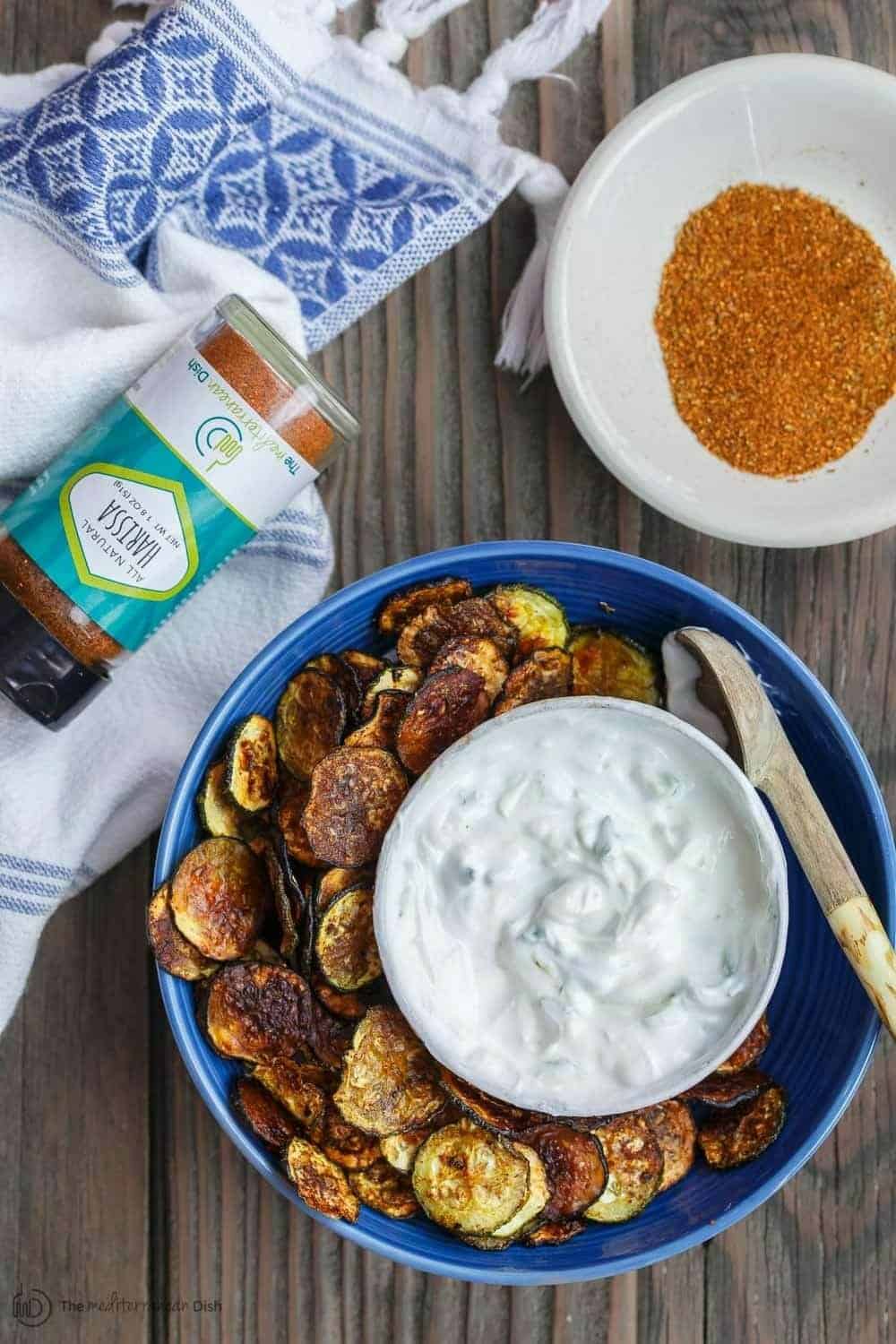 Zucchini Chips with a bowl of Harissa spice blend served on the side with Greek Tzatziki Dip