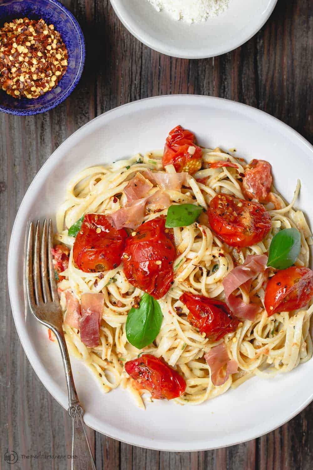 Carbonara Recipe with Roasted Tomatoes | The Mediterranean Dish. A lighter, and flavor-packed cabornara recipes with garlic roasted tomatoes and fresh herbs. You can add ribbons of prosciutto, if you like. A couple of tricks make a perfectly creamy carbonara. Recipe from themediterraneandish.com #pasta #pastarecipe #italianfood #mediterraneandiet #carbonara #easyrecipe