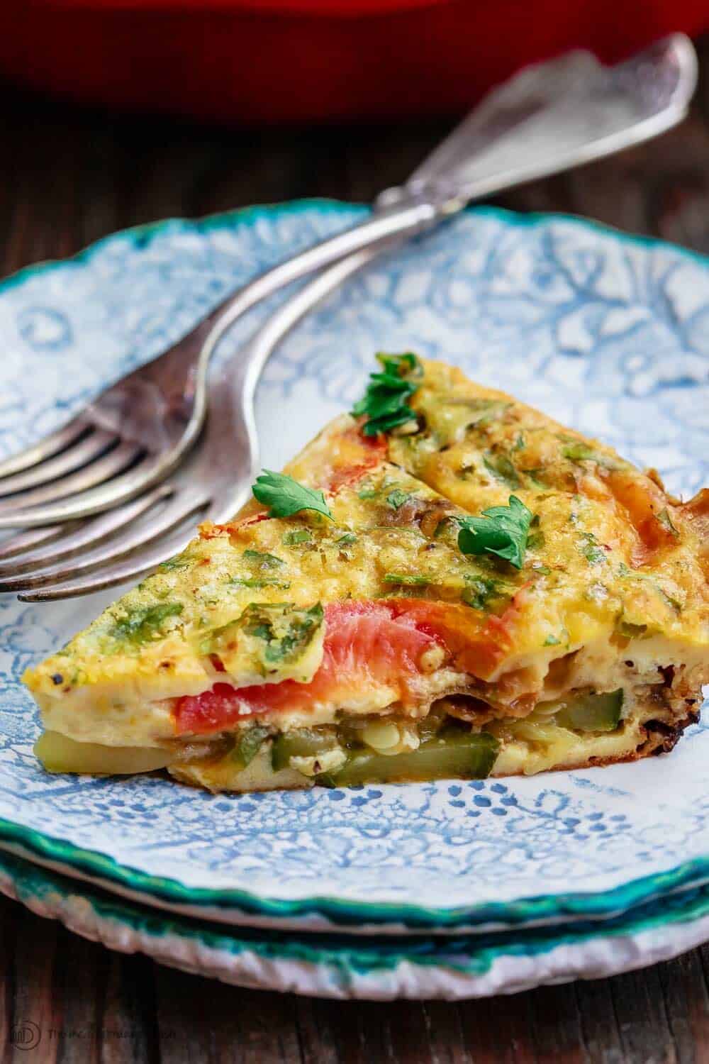 Crustless Zucchini Quiche Recipe | The Mediterranean Dish. Simple crustless zucchini quiche recipe with fresh herbs, tomatoes, and shallots. Perfect for breakfast, lunch, or a light dinner. See our suggestions for what to serve along. #zucchini #quiche #crustlessquiche #zucchinirecipe #breakfast #brunch #holidaybrunch #vegetarianrecipes #savorypie #eggs #mediterraneandiet #mediterraneanrecipes