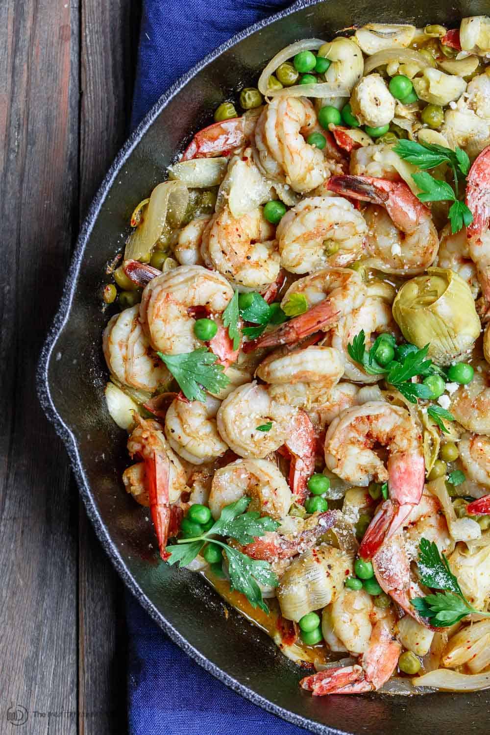 Easy garlic shrimp recipe with peas and artichokes! A quick and bright one-skillet meal. Be sure to see our suggestions for what to serve along. Recipe from TheMediterraneanDish.com #shrimp #glutenfree #mediterraneandiet