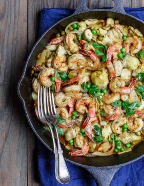 Easy garlic shrimp recipe with peas and artichokes! A quick and bright one-skillet meal. Be sure to see our suggestions for what to serve along. Recipe from TheMediterraneanDish.com #shrimp #glutenfree #mediterraneandiet