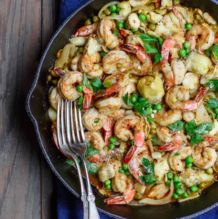 Easy garlic shrimp recipe with peas and artichokes! A quick and bright one-skillet meal. Be sure to see our suggestions for what to serve along. Recipe from TheMediterraneanDish.com #shrimp #glutenfree #mediterraneandiet