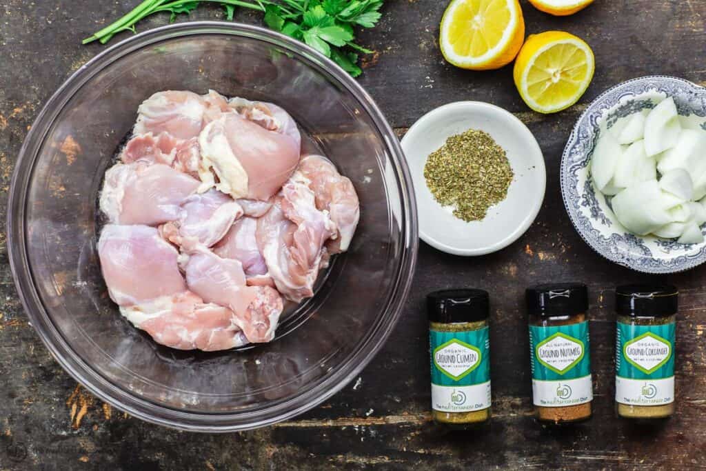 Ingredients for lemon chicken including chicken, spices, lemon, fresh parsley, garlic and onion