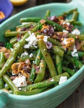Greek Green Bean Salad Recipe | The Mediterranean Dish. Perfectly tender, flavor-packed green bean salad prepared Greek style. A garlicy, zesty dressing pulls it together, and a sprinkle of feta and chopped marinated olives take it to a new level of delicious. Get the easy recipe on themediterraneandish.com #greenbeans #greekfood #greekrecipe #mediterraneanrecipe #mediterraneandiet
