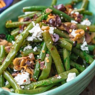 Greek Green Bean Salad Recipe | The Mediterranean Dish. Perfectly tender, flavor-packed green bean salad prepared Greek style. A garlicy, zesty dressing pulls it together, and a sprinkle of feta and chopped marinated olives take it to a new level of delicious. Get the easy recipe on themediterraneandish.com #greenbeans #greekfood #greekrecipe #mediterraneanrecipe #mediterraneandiet