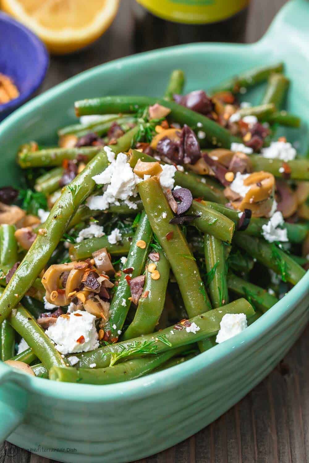 Greek Green Bean Salad Recipe | The Mediterranean Dish. Perfectly tender, flavor-packed green bean salad prepared Greek style. A garlicy, zesty dressing pulls it together, and a sprinkle of feta and chopped marinated olives take it to a new level of delicious. Get the easy recipe on themediterraneandish.com #greenbeans #greekfood #greekrecipe #mediterraneanrecipe #mediterraneandiet