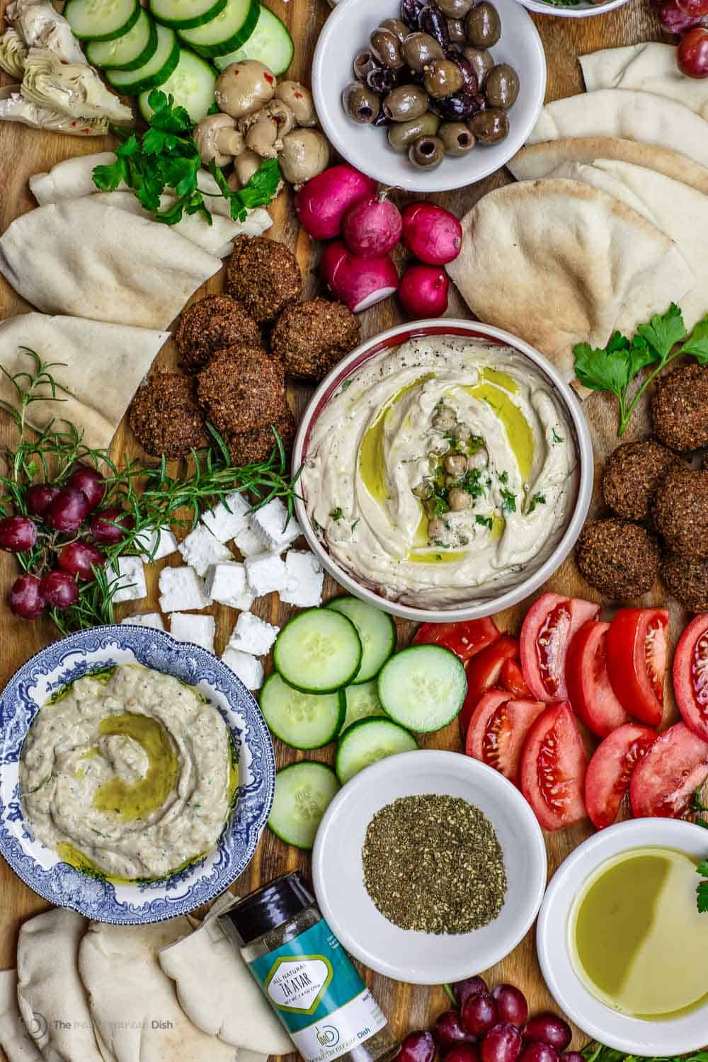 Mediterranean Diet Breakfast Board with falafel, hummus, black olives, feta cheese and veggies, served on a board.