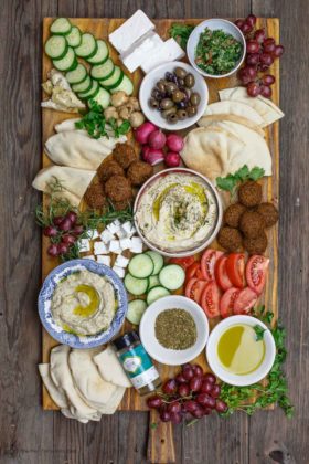 Mediterranean breakfast board with falfel, hummus, baba ganoush, fresh sliced vegetables and olives