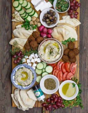 Mediterranean breakfast board with falfel, hummus, baba ganoush, fresh sliced vegetables and olives