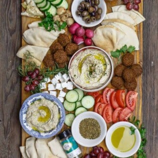 Mediterranean breakfast board with falfel, hummus, baba ganoush, fresh sliced vegetables and olives
