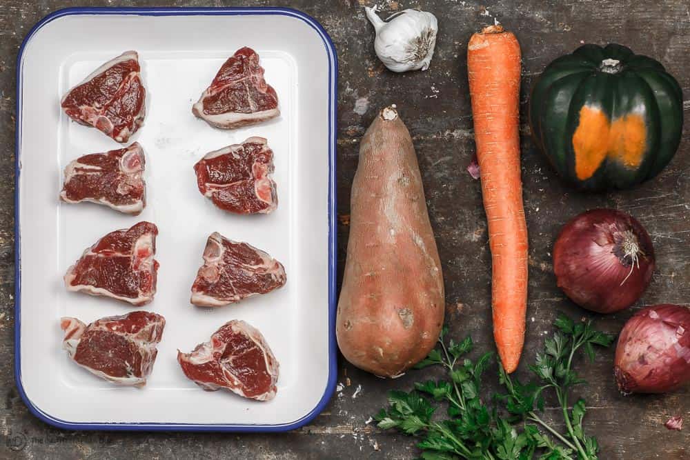 Ingredients for baked lamb chops recipe. Lamb chops, sweet potato, garlic, carrot, acorn squash, and fresh parsley