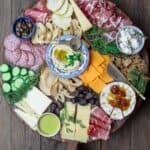 Best Cheese Board with assorted cheeses, cured meats, olives, cucumbers, and dried fruits