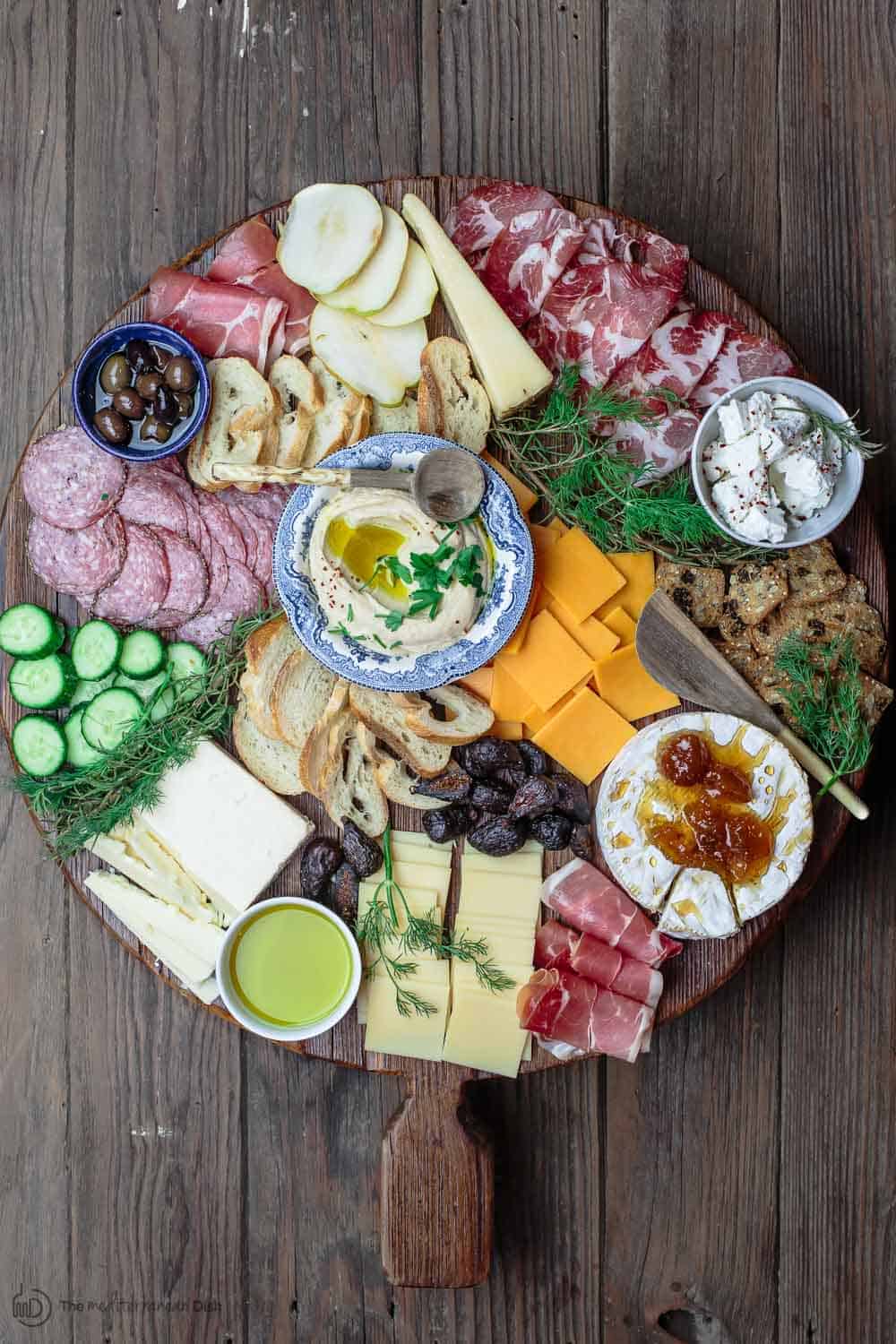 Best Cheese Board with assorted cheeses, cured meats, olives, cucumbers, and dried fruits