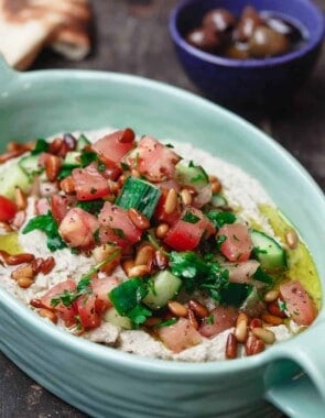 Smoky Eggplant Dip Baba Ganoush, topped with olive oil, pine nuts, and a few scoops of Mediterranean salad