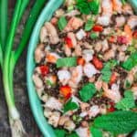 Tuscan White Bean Salad with shrimp, lentils, crunchy vegetables and fresh herbs. A garnish of scallions and fresh mint