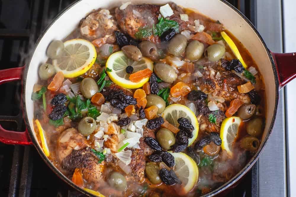 Lemons, olives, dried fruit, and liquid added to Moroccan chicken