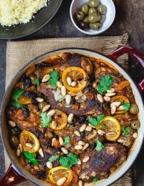 Moroccan chicken with lemons, olives, and dried fruit. Garnished with fresh cilantro and toasted almonds and served with couscous and more olives to the side